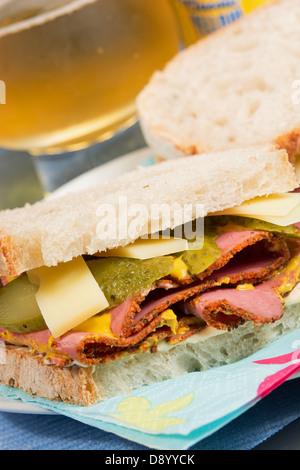 Ein Deli-Style Sandwich von Pastrami, Emmentaler Käse, in Scheiben geschnittene Gurken, Senf und Chili-Mayonnaise auf Sauerteig Brot. Stockfoto