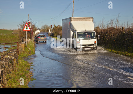 Der Verkehr bahnt sich seinen Weg durch eine überflutete Straße nach Winterregen, in der Nähe des Flusses Parrett, Martock, in den Somerset Levels, Somerset, Großbritannien. Stockfoto