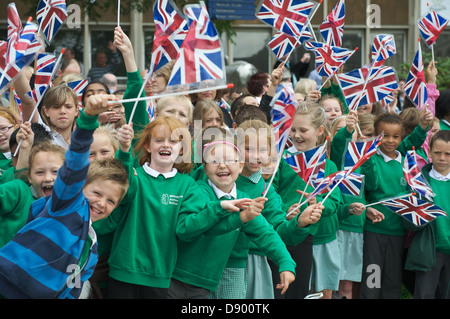 Schülerinnen und Schüler zuwinken eine militärische Homecoming Parade Union Jack-Flaggen. Stockfoto