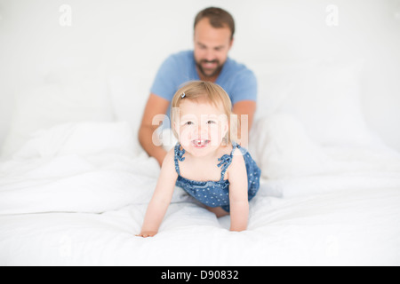 Glückliche kleine Mädchen mit dem Vater im Bett Stockfoto