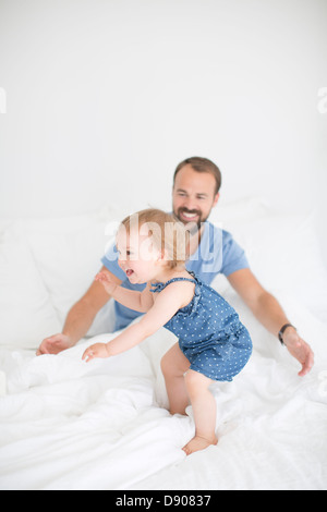 Glückliche kleine Mädchen mit dem Vater im Bett Stockfoto