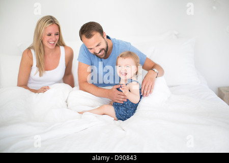 Eltern mit kleinen Tochter Entspannung im Bett Stockfoto