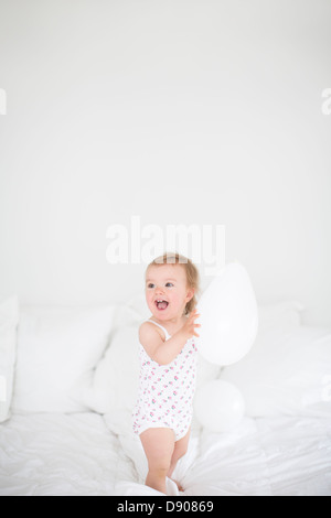 Kleine Mädchen stehen auf Bett und hält Ballon Stockfoto