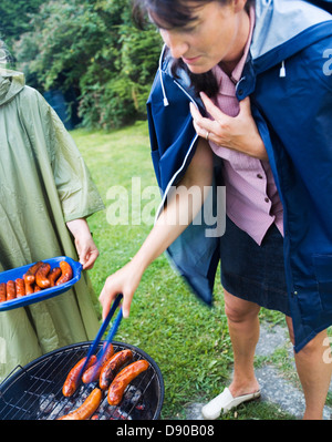 Eine Frau, Grillen bei Regenwetter, Schweden. Stockfoto