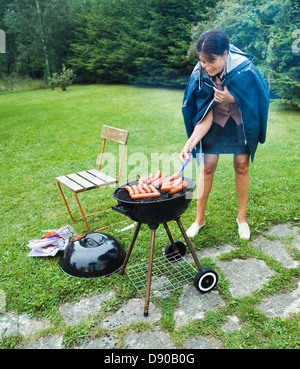Eine Frau, die Würstchen bei Regenwetter, Schweden. Stockfoto