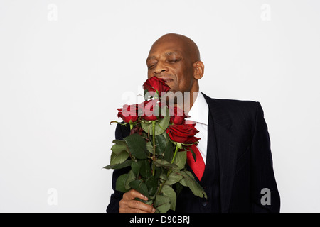 Ein Mann in einem Anzug mit einem Strauß roter Rosen. Stockfoto