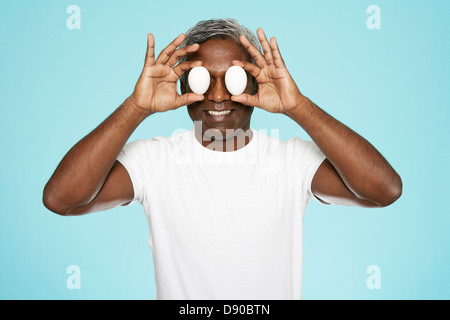 Porträt von einem Mann mittleren Alters, mit Eiern vor seinen Augen. Stockfoto