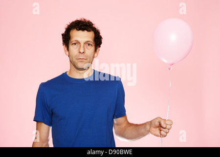 Ein Mann mittleren Alters mit einem rosa Ballon. Stockfoto