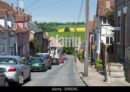 Häuser und geparkte Autos in Prentice Street, Lavenham, Suffolk, England, mit Feldern jenseits. Stockfoto