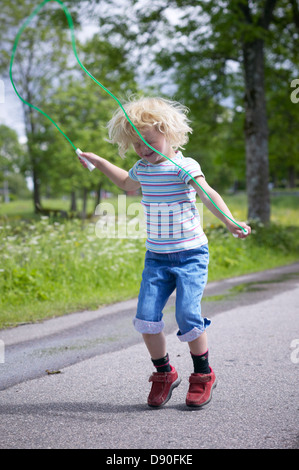Mädchen spielen mit Seilspringen auf Straße Stockfoto