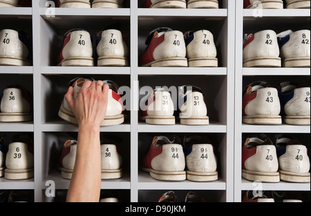 Hand Schuhe in Regalen in einer Bowlingbahn Kommissionierung. Stockfoto