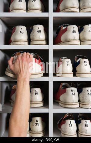 Hand Schuhe in Regalen in einer Bowlingbahn Kommissionierung. Stockfoto