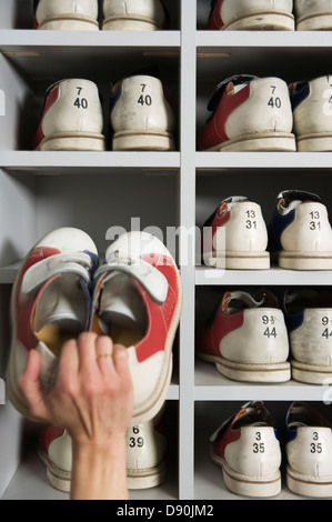 Hand Schuhe in Regalen in einer Bowlingbahn Kommissionierung. Stockfoto