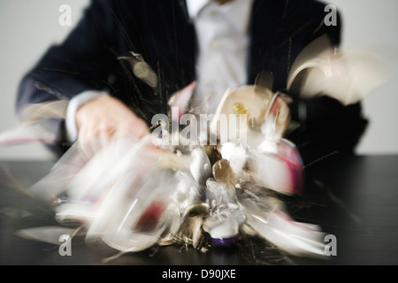 Ein Mann mit einem Hammer ein Sparschwein zu brechen. Stockfoto