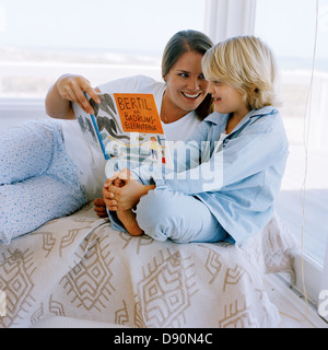 Mutter und Sohn liegend auf dem Bett ein Buch lesen, Schweden. Stockfoto