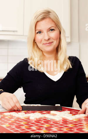 Porträt der jungen Frau Brettspiel in Küche Stockfoto