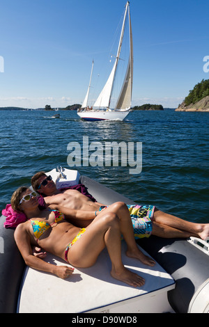 Junges Paar Sonnenbaden am Schlauchboot Stockfoto