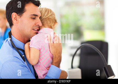 fürsorgliche Kinderarzt umarmt ein krankes Babymädchen Stockfoto