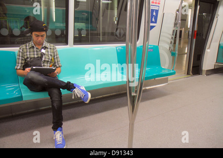 Singapur SMRT, East West Green Line, Schnellverkehr, Passagierkabine, asiatischer Mann Männer, Passagierfahrer Fahrer, Fahrer, sitzend, Laptop, Noteb Stockfoto