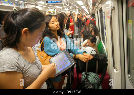 Singapur Lavender MRT-Station, East West Line, U-Bahn-Zug, asiatische Frau weibliche Frauen, Pendler, Tablet, Apple iPad, mit, stehend, Sing130201041 Stockfoto
