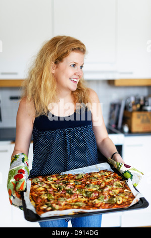 Yong lächelnde Frau mit frisch Pizza gemacht Stockfoto
