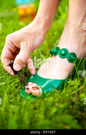 Eine Frau malt ihre Fußnägel in den Rasen. Stockfoto