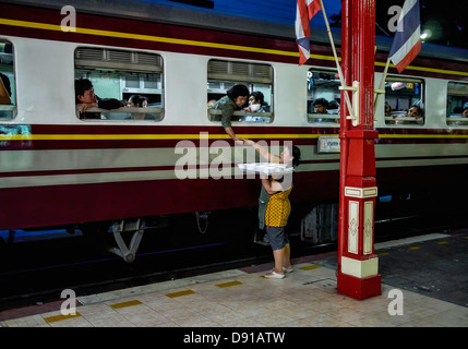 Nachtaufnahme von einem thailändischen Zug am Bahnhof und Kauf von Lebensmitteln aus einem unternehmungslustigen lokale Anbieter Passagiere. S. E. Asien Thailand Stockfoto