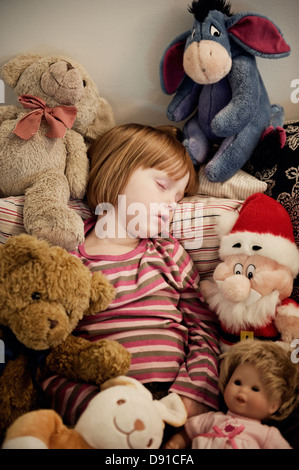 Mädchen schläft unter Kuscheltiere, Schweden. Stockfoto