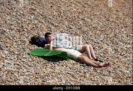 Brighton, Sussex, UK. 8. Juli 2013. Die Sonne kommt heraus, wie dieser Herr die bekannte Tageszeitung bei heißem Wetter am Strand von Brighton heute liest Stockfoto