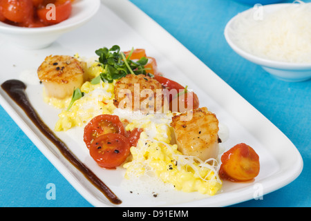 Safran-Risotto mit gegrillten Jakobsmuscheln und Cherry-Tomaten-sauce Stockfoto