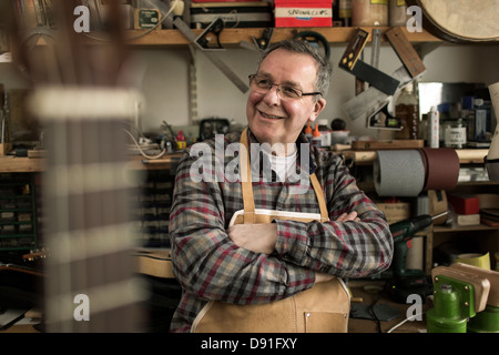 Gitarrenbauer stehend in Werkstatt, Lächeln Stockfoto