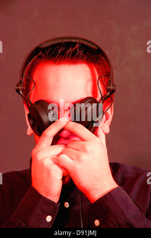 Junger Mann hält seine Augen geschlossen mit Kopfhörer Stockfoto