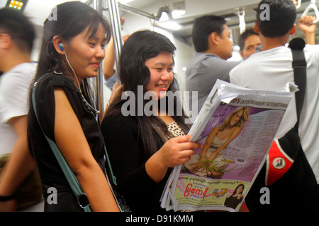 Singapur MRT East West Line, U-Bahn-Zug, Fahrerkabine, Fahrer, Pendler, asiatische Frau weibliche Frauen, stehend, lesen, Zeitung, Sing130203175 Stockfoto