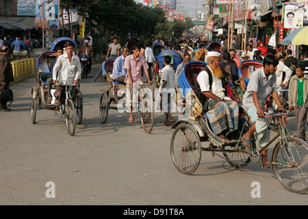 Rikschas, die Passagiere auf der belebten Straße Bogra, nördlich von Bangladesch Stockfoto