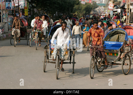 Rikschas, die Passagiere auf der belebten Straße Bogra, nördlich von Bangladesch Stockfoto