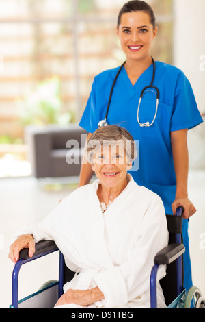 hübsche junge Krankenschwester ältere Frau im Rollstuhl schieben Stockfoto