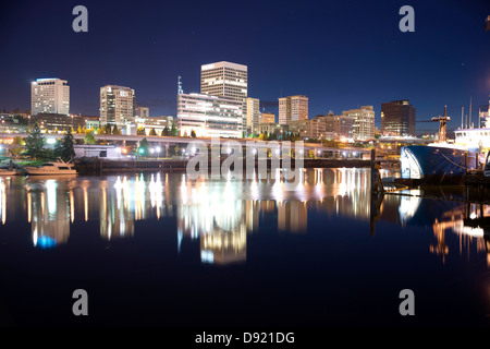 Nacht fällt hinter der Skyline von Tacoma und Boote auf Thea Foss Waterway Stockfoto