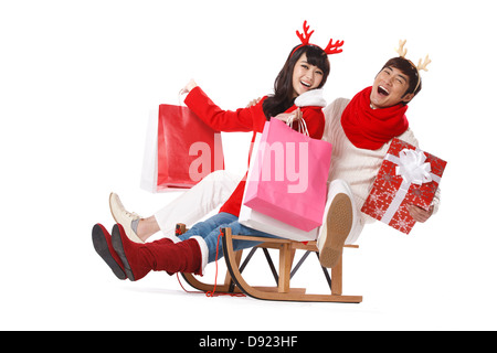 Junges Paar Weihnachtsgeschenke auf Schlitten halten Stockfoto