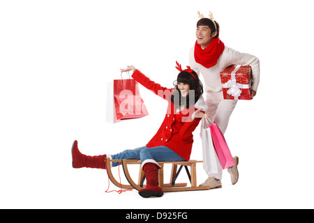 Junges Paar halten Weihnachtsgeschenk auf Schlitten Stockfoto