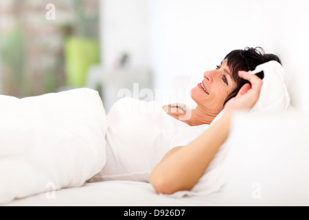 attraktive mittlere gealterte Frau liegt auf Bett entspannen Stockfoto