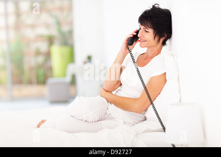 ziemlich mittlere gealterte Frau am Festnetz-Telefon am Bett Stockfoto