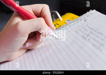 Nahaufnahme von junge Frau/Frau, schreiben über Spiral-Notizbuch mit einem roten Stift mit gepflegten Fingernägeln. Stockfoto