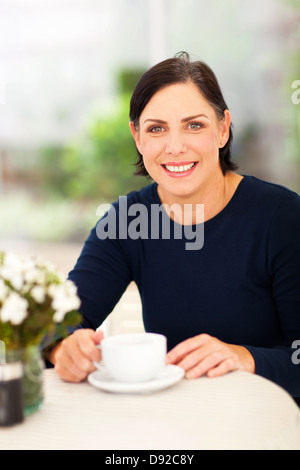 schöne mittlere gealterte Frau zu Hause mit einer Tasse Kaffee entspannen Stockfoto