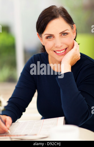 elegante senior Frau tun Kreuzworträtsel auf Zeitung Stockfoto