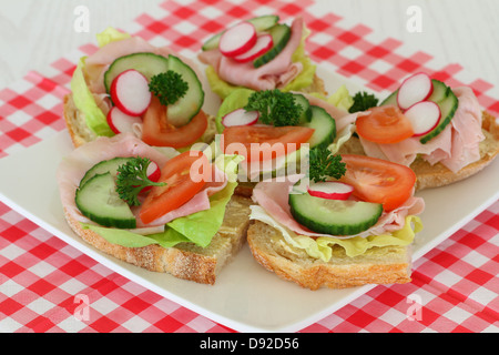 Brötchen mit Schinken und Salat auf karierte Serviette Stockfoto