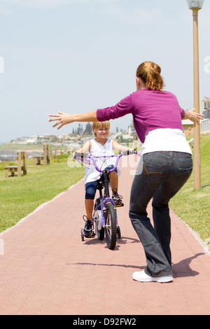 glückliche kleine Mädchen mit dem Fahrrad in Richtung ihrer Mutter Stockfoto