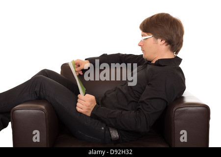 Mann mit Brille lesen Sie ein Buch ruhig in seinem braunen Leder entworfen Sessel. Isoliert auf weißem Hintergrund. Stockfoto