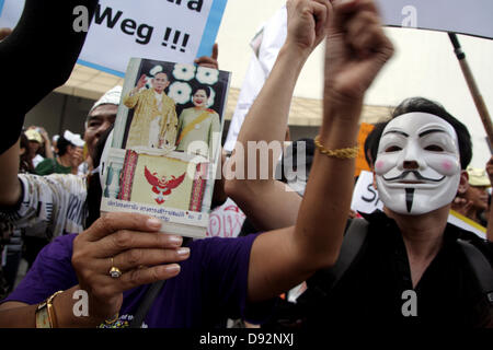 Bangkok, Thailand. 9. Juni 2013. Ein Demonstrant hält Thailands König Bhumibol Adulyadej und Thailands Königin Sirikit Foto beim Protest gegen die Bangkok Kunst- und Kulturzentrum.  Demonstranten tragen 'Guy Fawkes' weiterhin in Bangkok und anderen Teilen von Thailand gegen die Regierung von Yingluck Shinawatra, rally, die Gegner sagen, ist eine "Marionette" von flüchtigen ehemaligen premier Thaksin Shinawatra gesteuert. Bildnachweis: John Vincent/Alamy Live-Nachrichten Stockfoto