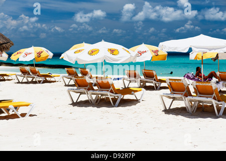 Liegestühle und Sonnenschirme auf einem Strand Playa Norte, Isla Mujeres, Mexiko Stockfoto