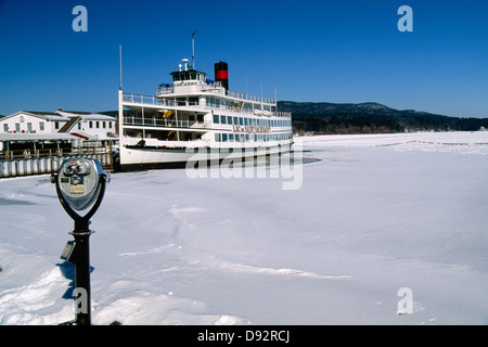 Sightseeing-Boot vertäut am Pier in einem zugefrorenen See, Lake George Village, New York Stockfoto